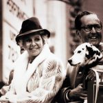 A man and woman sit with a dalmatian