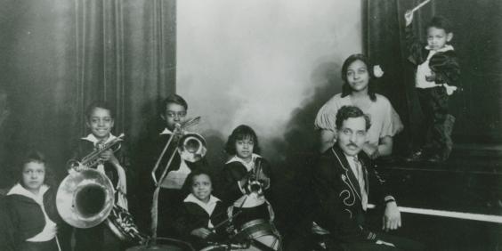 Dungill family, two adults, six children posing with musical instruments